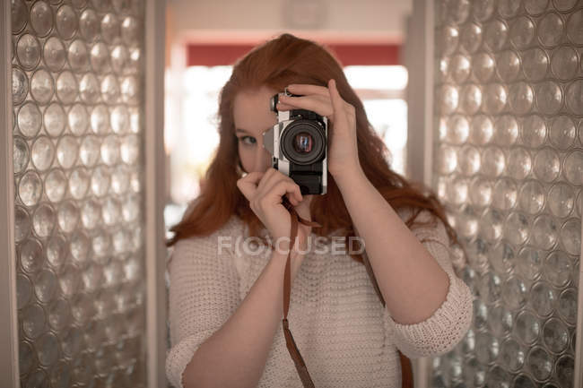 Mujer haciendo clic en la foto con cámara en casa - foto de stock