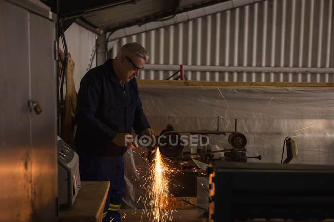 Worker shaping metal on machine in aircraft hangar — Stock Photo