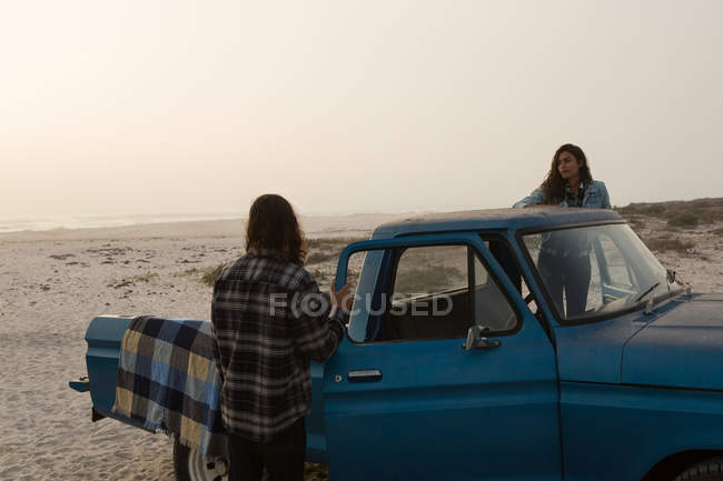 Coppia in piedi con il loro pick-up in spiaggia — Foto stock