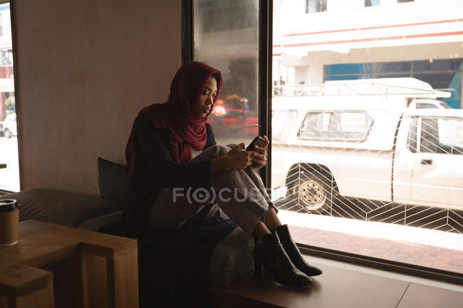 Donna d'affari in hijab utilizzando il telefono cellulare in mensa ufficio — Foto stock
