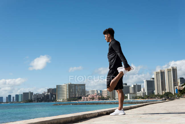 Молодий чоловік тренується біля моря в сонячний день — стокове фото