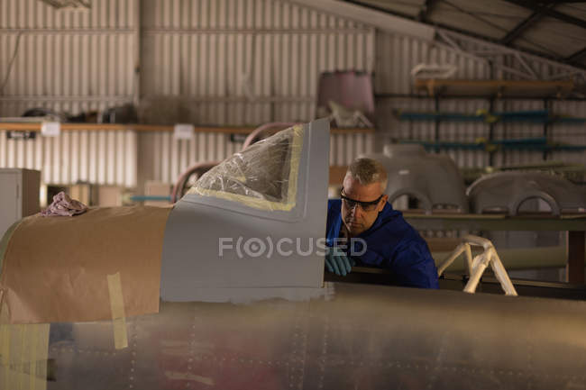 Engineer checking parts of plane in hanger — Stock Photo