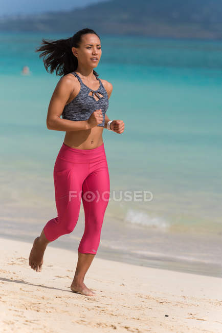 Femme jogging dans la plage par une journée ensoleillée — Photo de stock