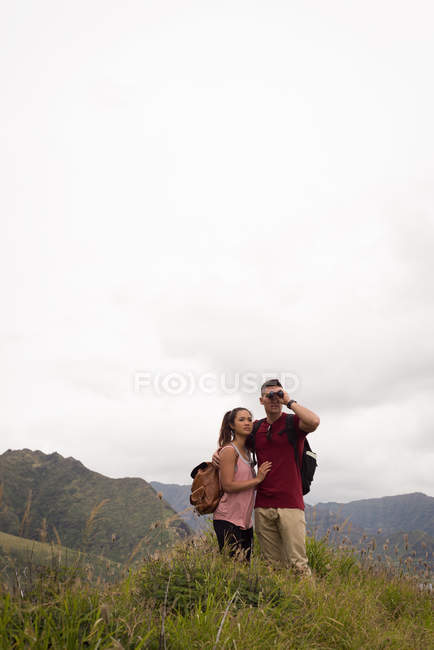 Romantic couple looking through binoculars in countryside — Stock Photo