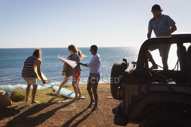 Gruppo di amici che rimuovono la tavola da surf dalla jeep — Foto stock