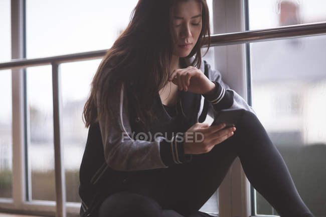 Young female dancer using mobile phone in dance studio — Stock Photo