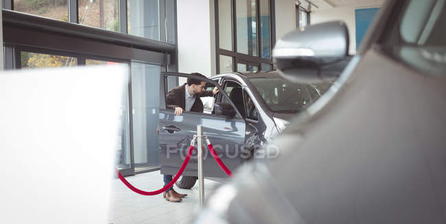 Salesman examining car at showroom — Stock Photo
