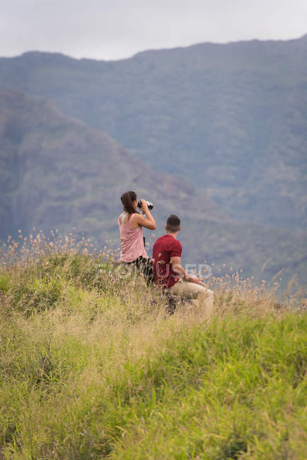 Hiker couple sitting in countryside, girl drinks from a thermos bottle — Stock Photo