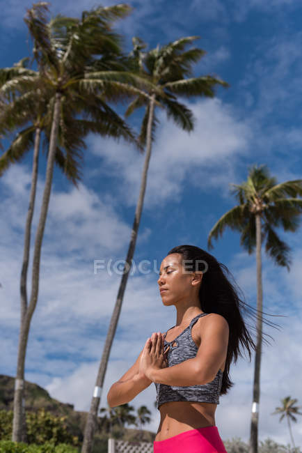 Femme effectuant du yoga à la plage par une journée ensoleillée — Photo de stock
