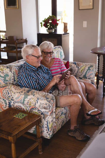 Couple aîné utilisant une tablette numérique dans le salon à la maison — Photo de stock