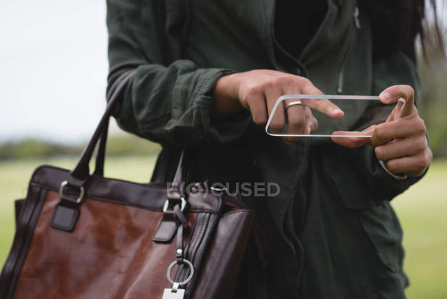Frau benutzt gläsernes Handy im Park — Stockfoto