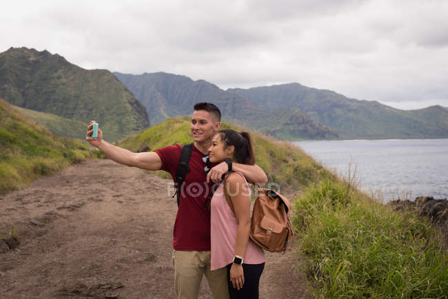 Romantic couple taking selfie with mobile phone in countryside — Stock Photo