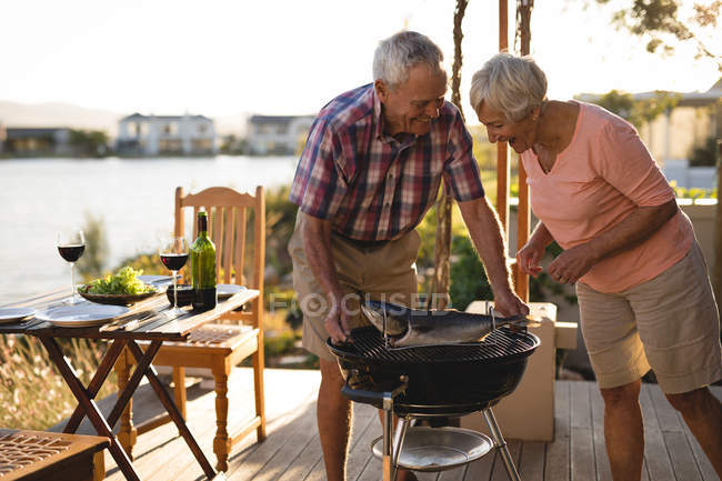 Coppia di anziani cucinare il pesce sul barbecue nel cortile — Foto stock