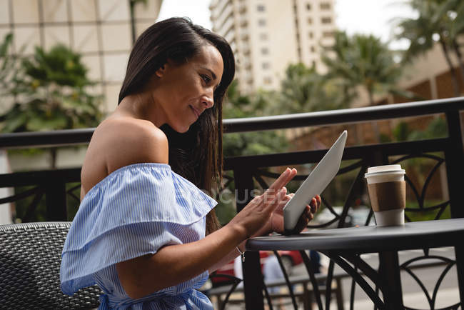Улыбающаяся красивая женщина с помощью цифрового планшета в кафе — стоковое фото