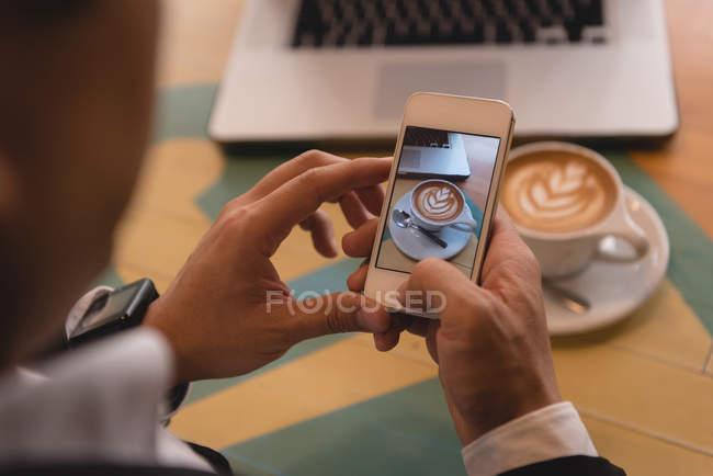 Крупный план бизнесмена, щёлкающего фото кофе в кафе — стоковое фото