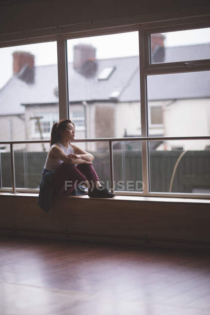 Dançarina feminina atenciosa olhando através da janela no estúdio de dança — Fotografia de Stock