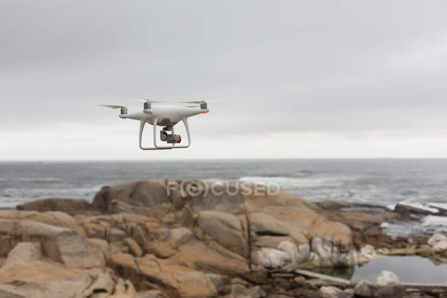 Drone flying in air over a sea — Stock Photo