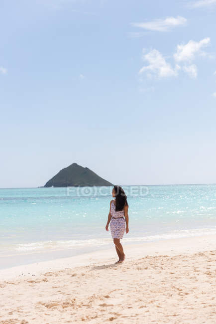 Женщина, гуляющая одна по пляжу в солнечный день — стоковое фото