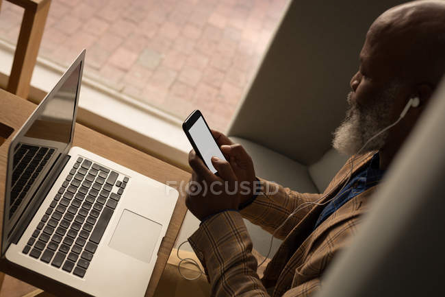 Diseñador gráfico senior usando laptop en cafetería en la oficina - foto de stock
