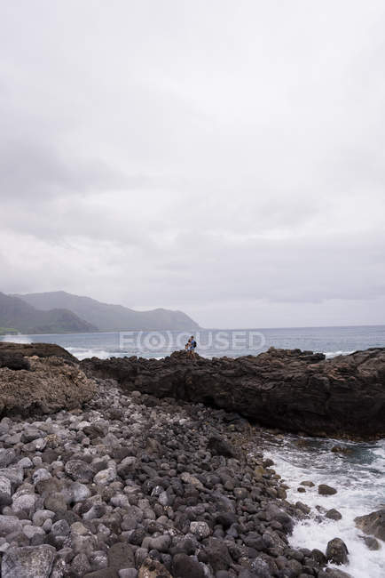 Casal de pé juntos perto do mar em um dia ensolarado — Fotografia de Stock