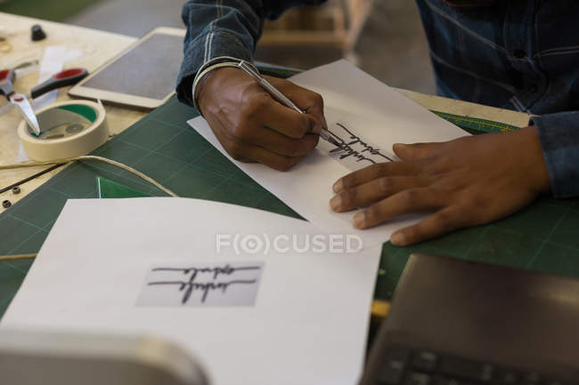Человек делает дизайн на бумаге в мастерской — стоковое фото