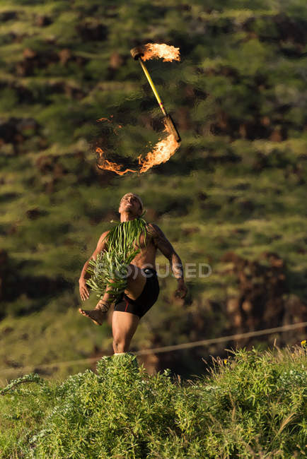 Danseur de feu masculin performant avec bâton de levi de feu près de la plage — Photo de stock