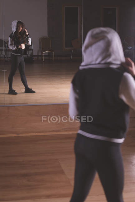 Молодая танцовщица смотрит в зеркало танцевальной студии — стоковое фото