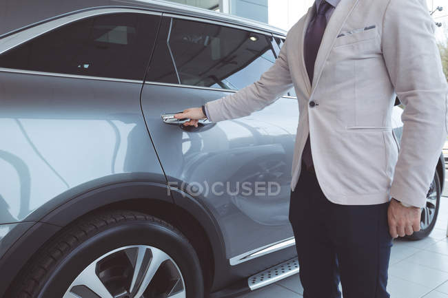 Mid section of salesman examining car at showroom — Stock Photo