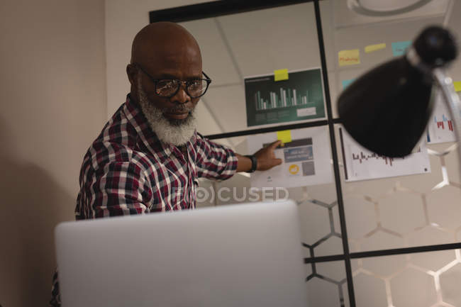 Senior graphic designer discussing over sticky notes in office — Stock Photo