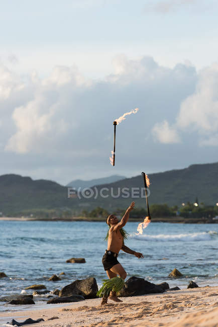 Maschio ballerino del fuoco che si esibisce con bastoni levi fuoco in spiaggia — Foto stock