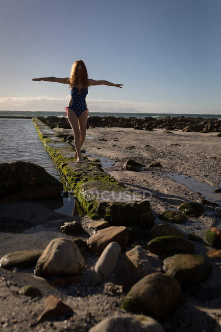 Femme bord de marche de la piscine en bord de mer par une journée ensoleillée — Photo de stock