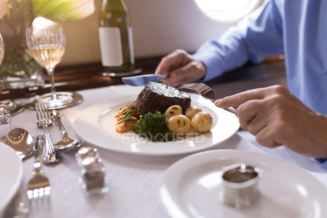 Sección media del hombre de negocios comiendo mientras viaja en jet privado - foto de stock