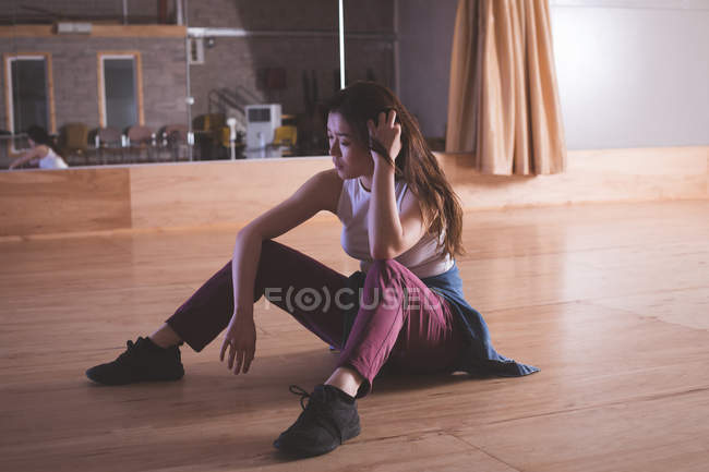 Thoughtful female dancer relaxing in dance studio — Stock Photo
