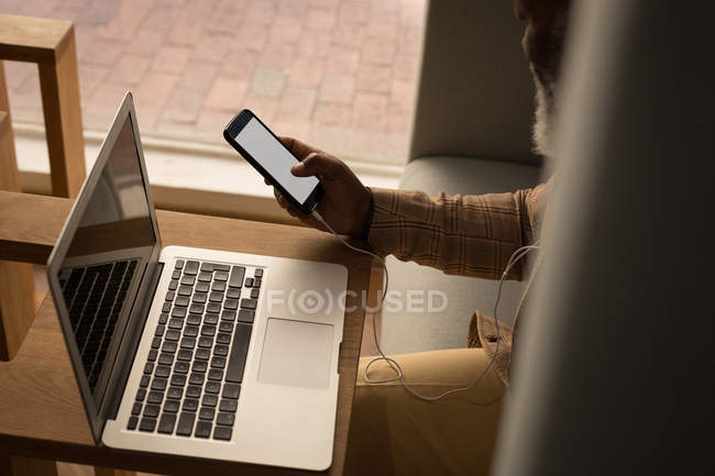 Designer gráfico sênior usando laptop na cafetaria no escritório — Fotografia de Stock