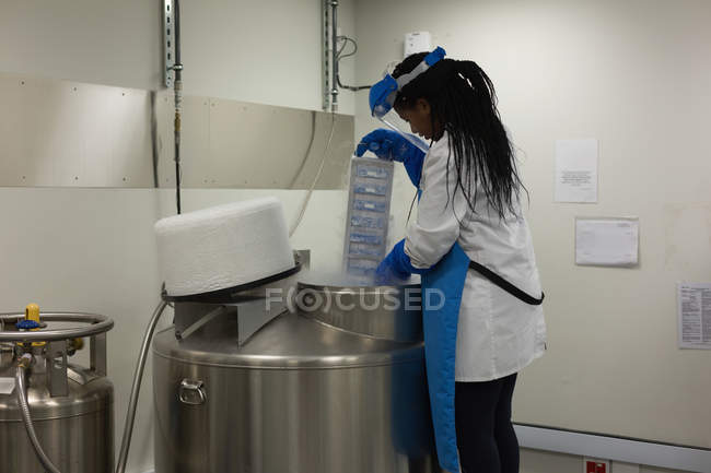 Female scientist removing medical samples from machine in lab — Stock Photo