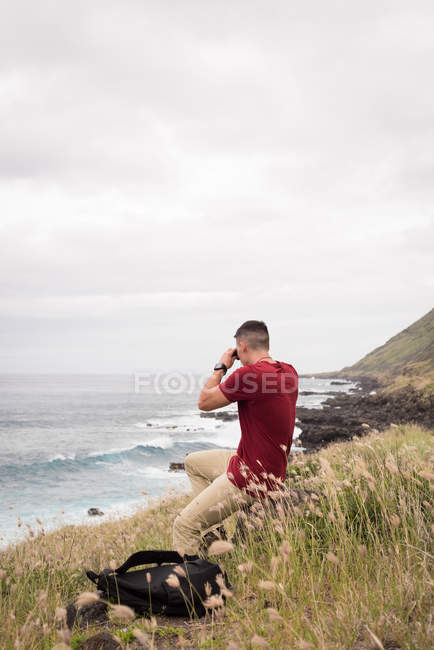 Homem olhando através de binóculos no campo em um dia ensolarado — Fotografia de Stock