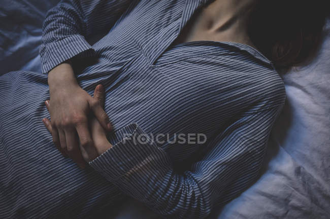 Metà sezione di donna sdraiata sul letto in camera da letto a casa — Foto stock