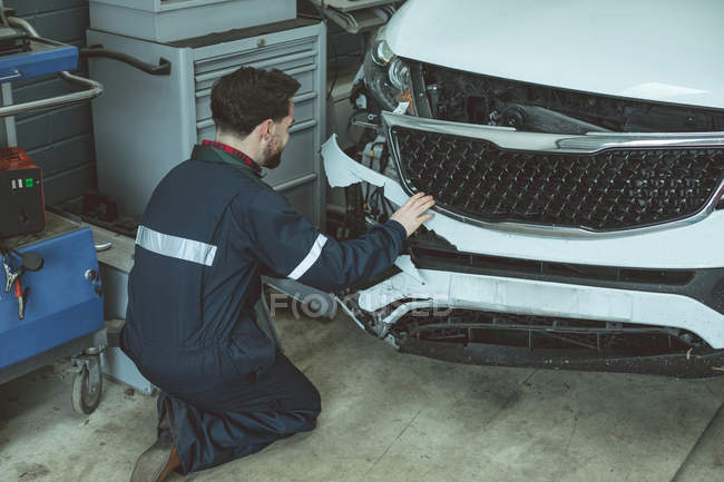 Mecánico examinar coche dañado en el garaje de reparación - foto de stock