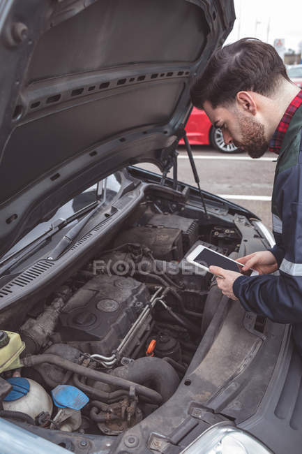 Mécanicien masculin utilisant tablette numérique au garage de réparation — Photo de stock
