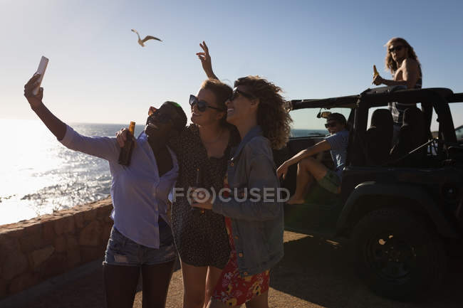 Grupo de amigos tirando selfie com celular na praia — Fotografia de Stock