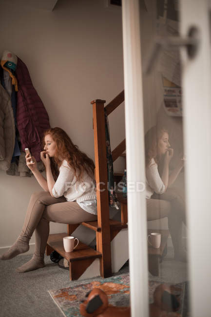 Красивая женщина с помощью мобильного телефона дома — стоковое фото
