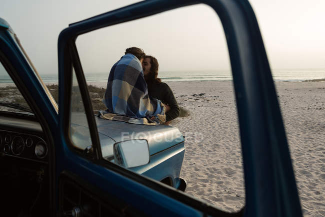 Couple romancing on a pickup truck bonnet in the beach — Stock Photo