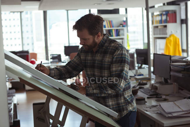 Architect designing on drafting table in the office — Stock Photo