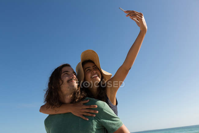 Casal tirando selfie com celular na praia — Fotografia de Stock