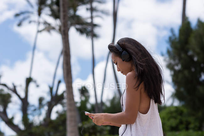 Jeune femme utilisant un téléphone portable à la plage — Photo de stock