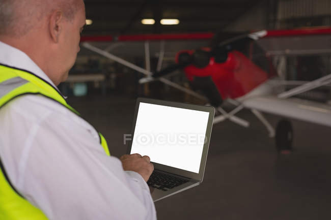 Membre d'équipage utilisant un ordinateur portable au hangar aérospatial — Photo de stock