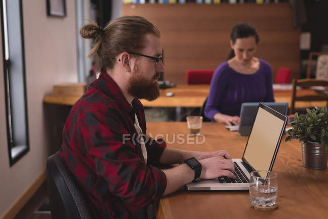 Executivo masculino usando laptop na mesa no escritório — Fotografia de Stock