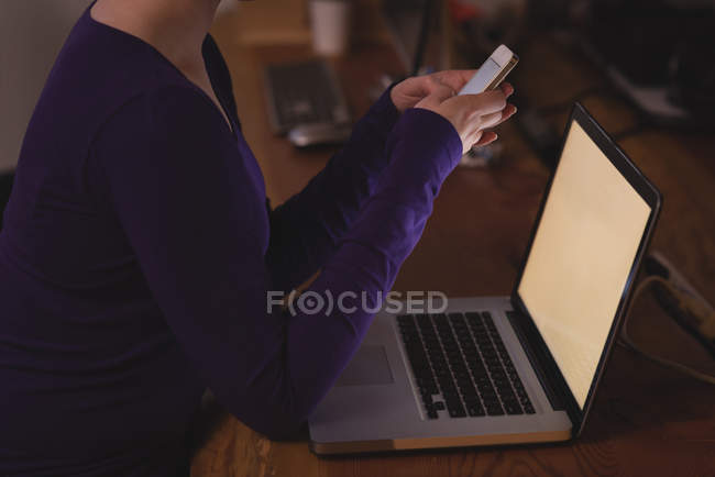Executivo feminino usando telefone celular na mesa no escritório — Fotografia de Stock