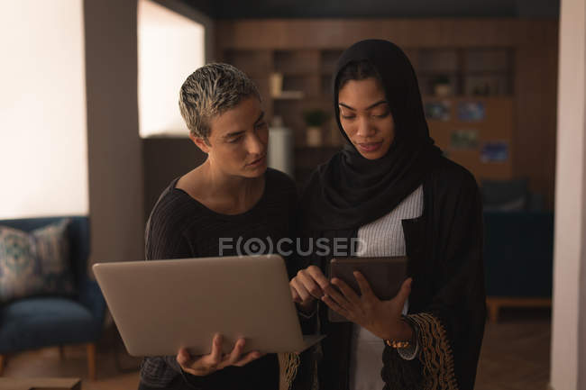 Compañeros de negocios usando laptop y tableta digital en la oficina - foto de stock