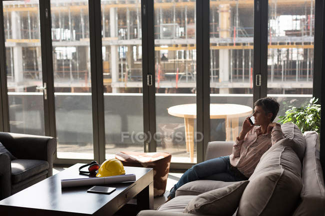 Arquiteta feminina conversando no celular no escritório — Fotografia de Stock